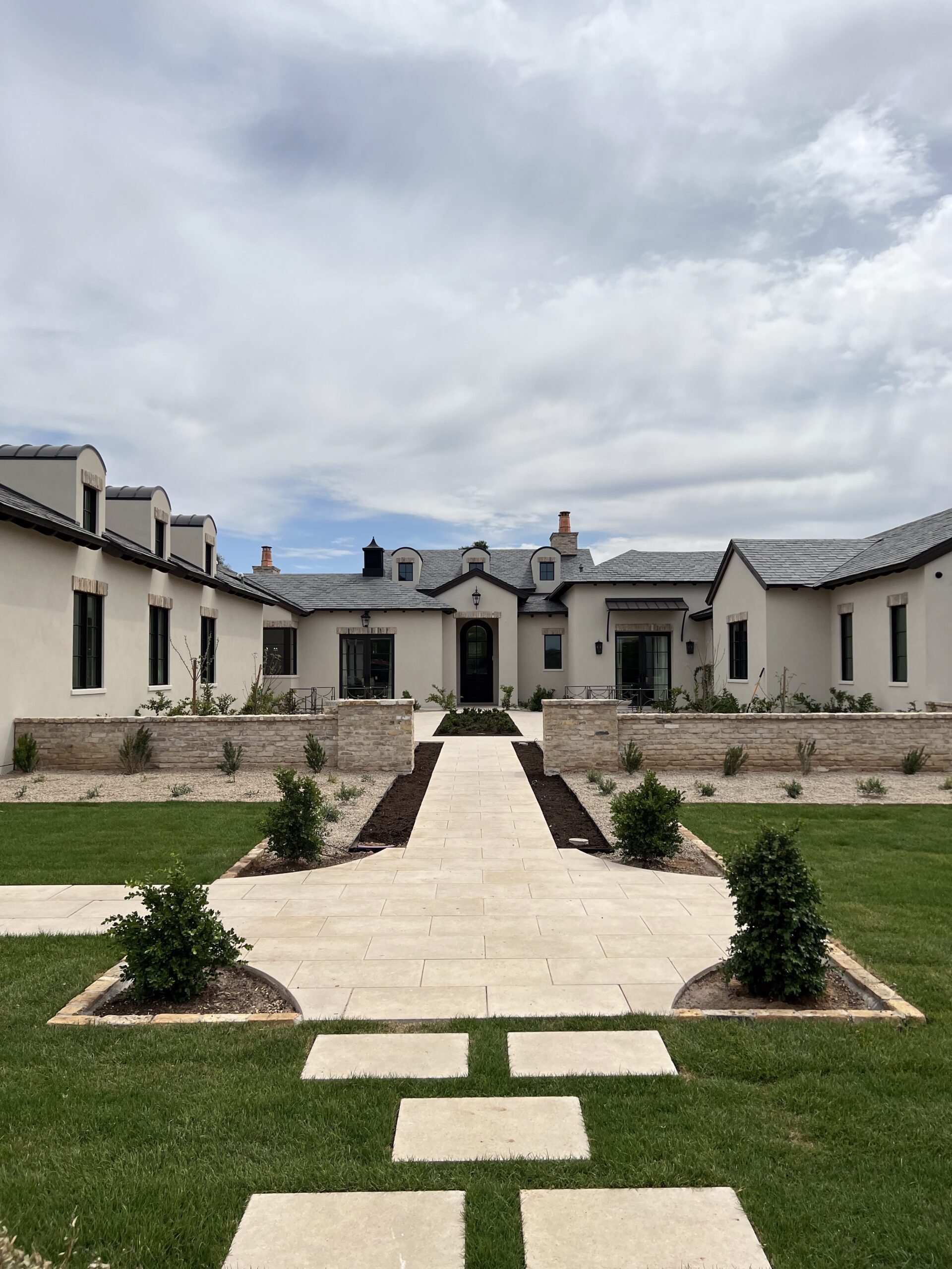 Aerial view of a large luxury estate with manicured front lawn, multiple roof peaks, and surrounding desert landscape.