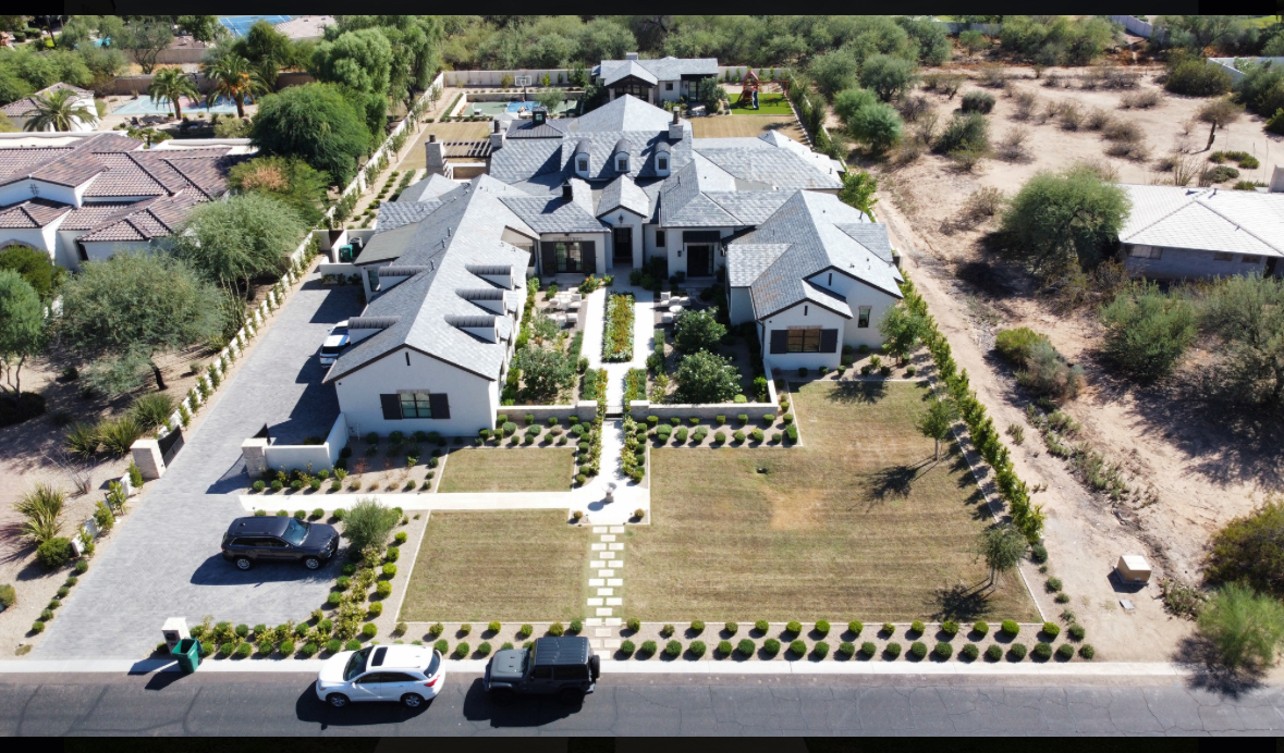 Elegant front courtyard with a central stone fountain, manicured pathways, and symmetrical landscaping leading to a luxury home.