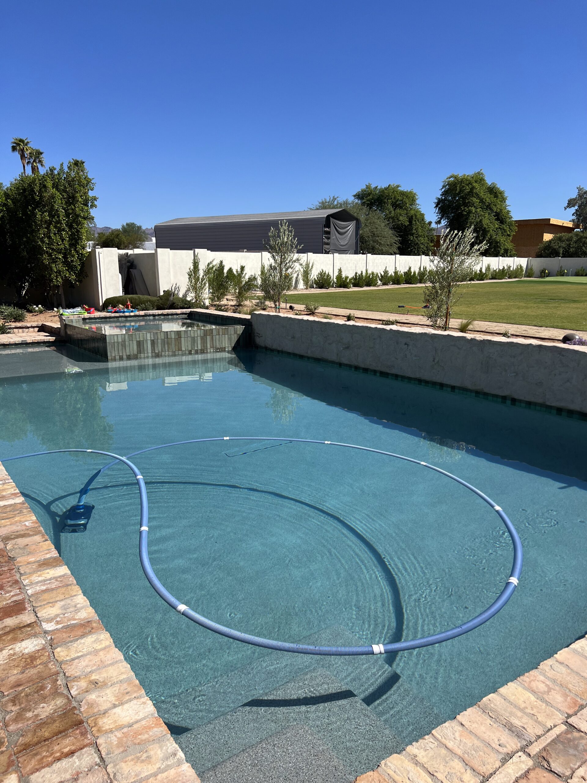 An outdoor pool with bricks on the side.