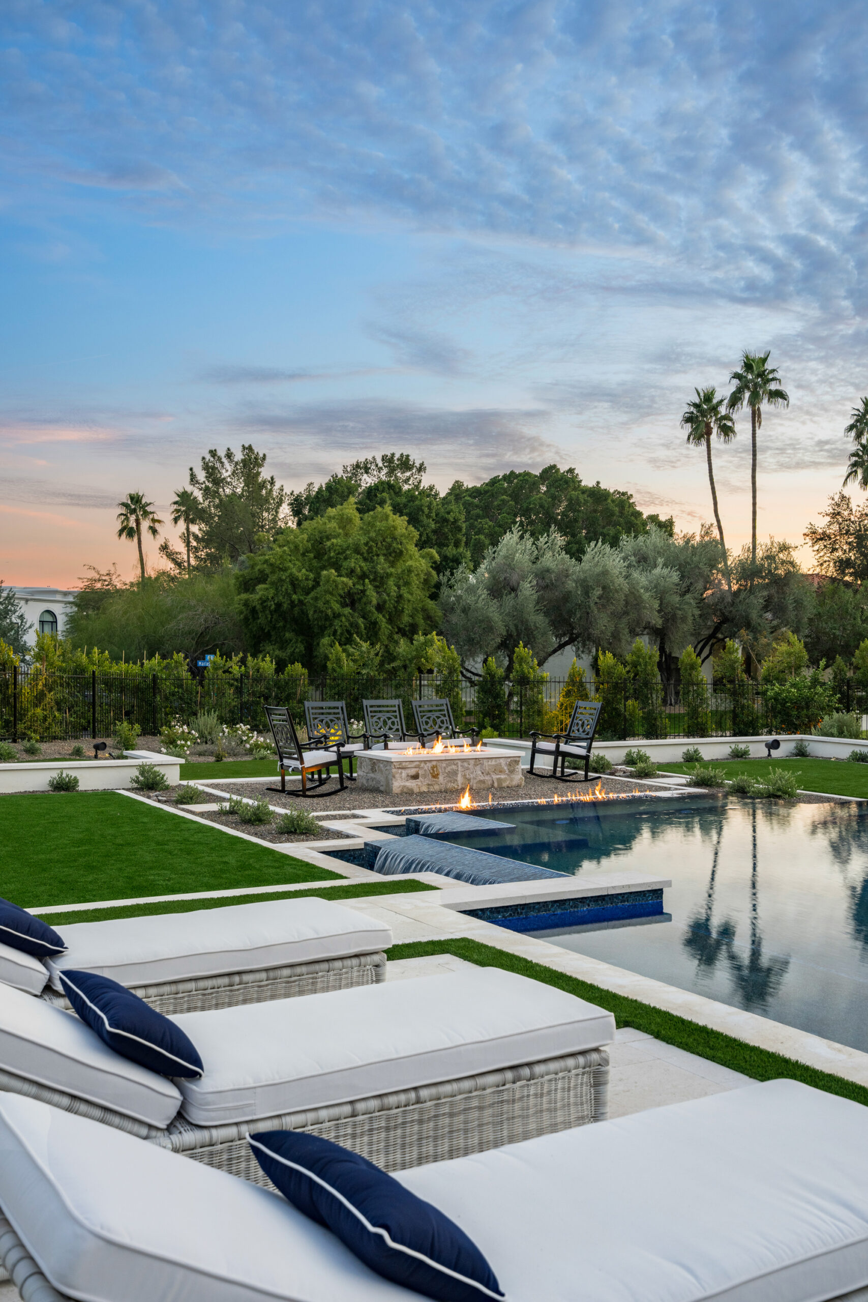 Poolside lounge chairs with trees and palm trees at sunset Innovative pools- 24th street