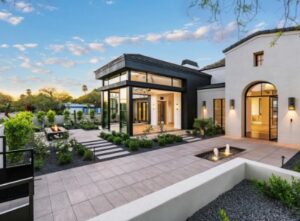 Modern home exterior with large windows, clean landscaping, and a courtyard fountain