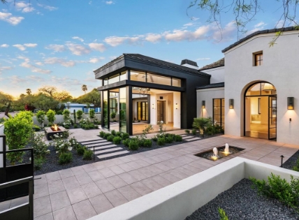 Modern home exterior with large windows, clean landscaping, and a courtyard fountain